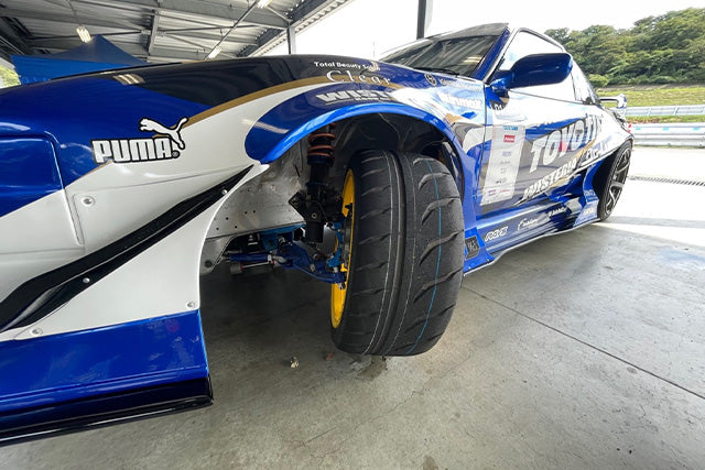 Drift car front wheel at full steering lock showing tire and suspension clearance