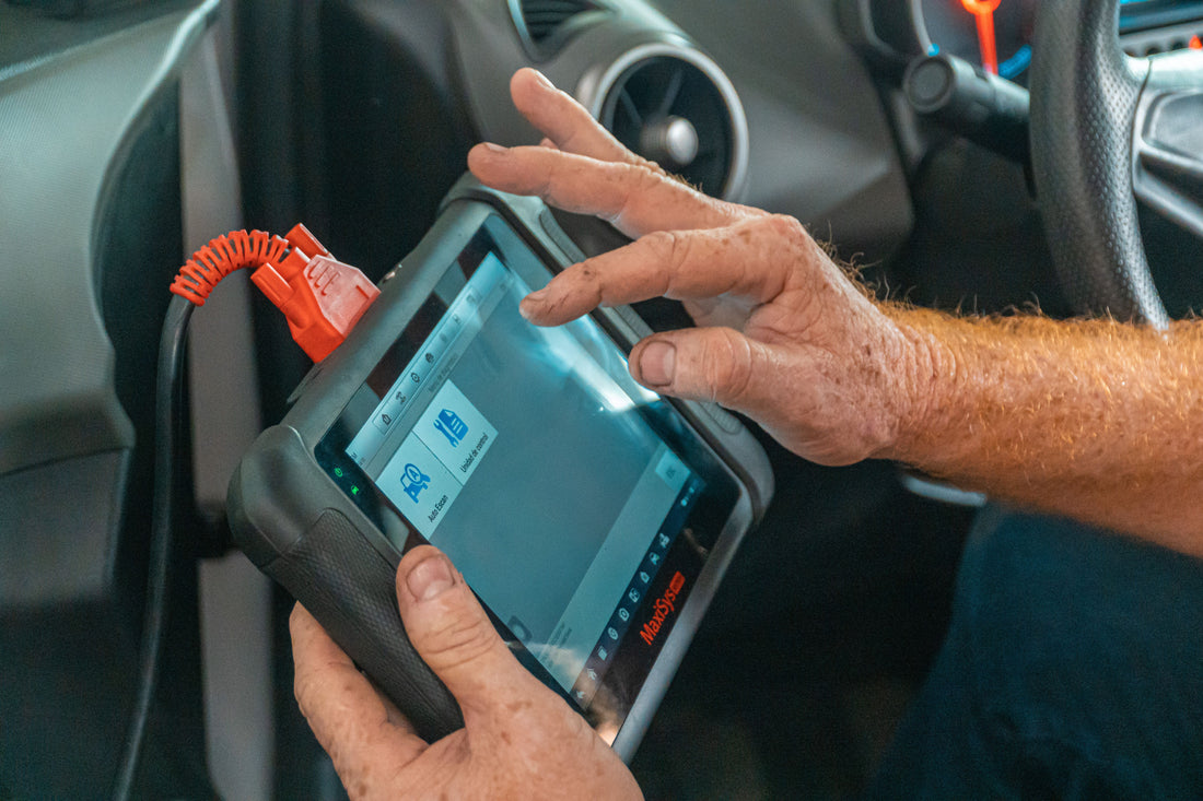 Technician using an automotive diagnostic scan tool inside a car