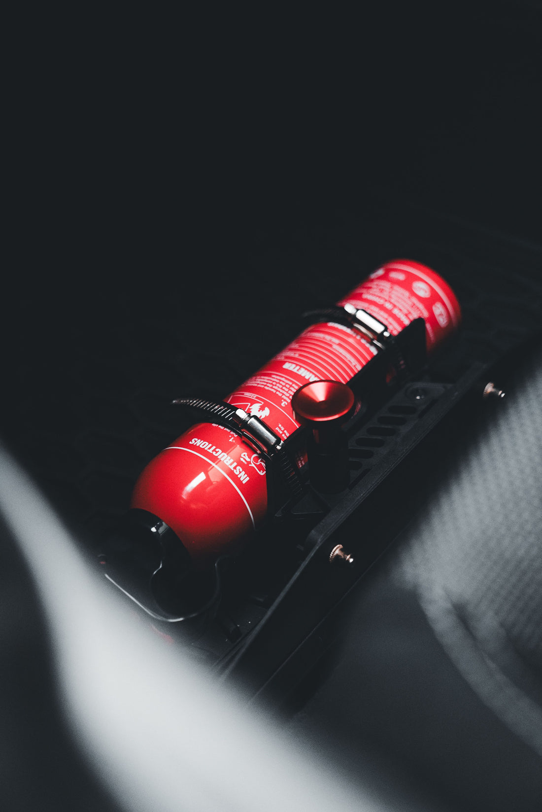 Representative photo of a red fire extinguisher mounted inside a vehicle; pictured equipment certification is not verified. Photo by Erik Mclean via Pexels.