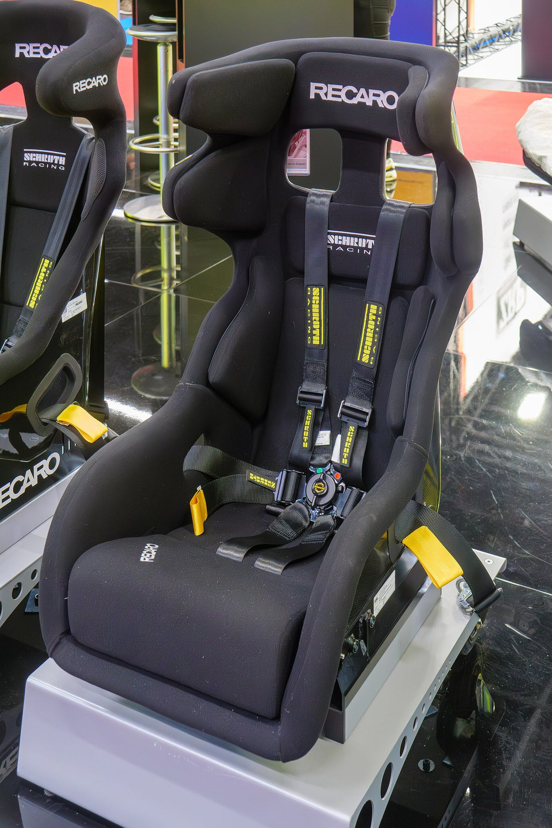 Recaro bucket seat with Schroth harness displayed at Professional MotorSport World Expo 2024; representative competition-seat image, not proof of current homologation. Photo by Matti Blume / Wikimedia Commons, CC BY-SA 4.0.