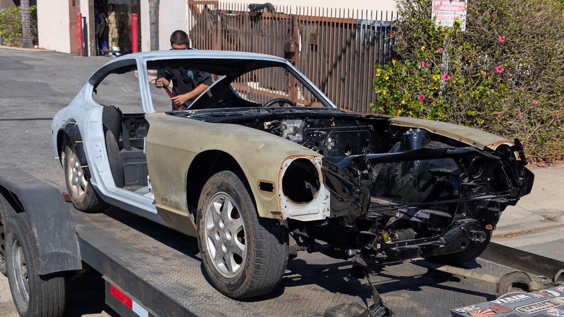 Race Club Datsun 280Z shell secured on a flatbed with its drivetrain and front bodywork removed for paint preparation