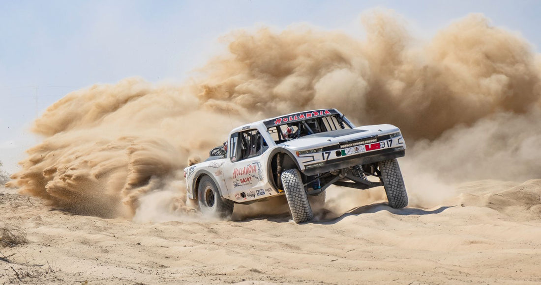 A white race truck turning through desert sand with a large dust plume. Representative photograph, not the 2026 Laughlin Desert Classic.