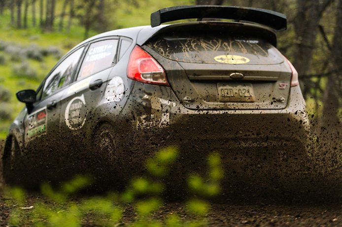 Rally car driving through a gravel forest stage at Tour de Forest in Washington.