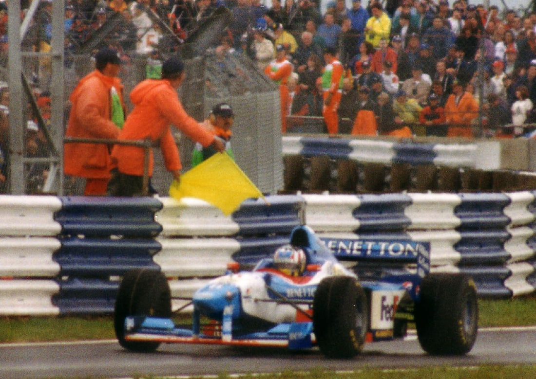 Alexander Wurz in a Benetton passing a yellow flag at Silverstone in 1997.