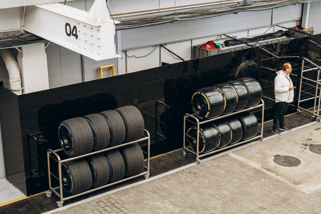Two racks of slick and treaded racing tires beside a pit garage.