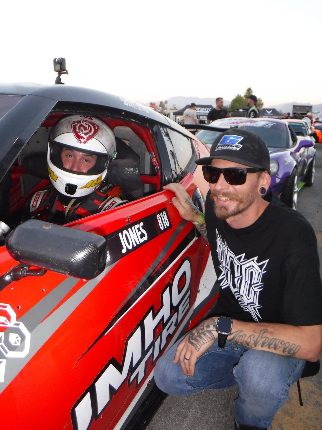Jeff Jones and Tim Keehnel talking beside a red race car in the hot-pit line.