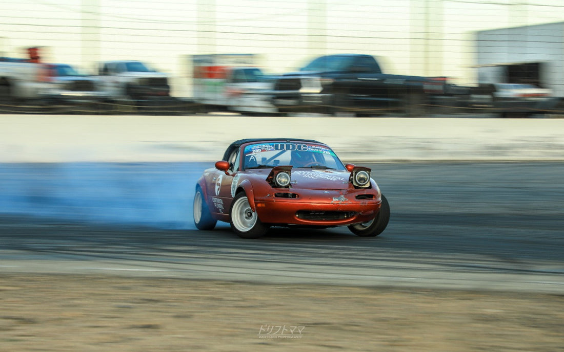Red Mazda Miata drifting through a track corner