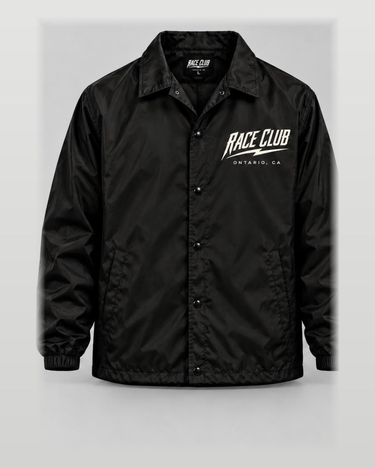 Front view of black Race Club snap-front coach jacket with left chest branding